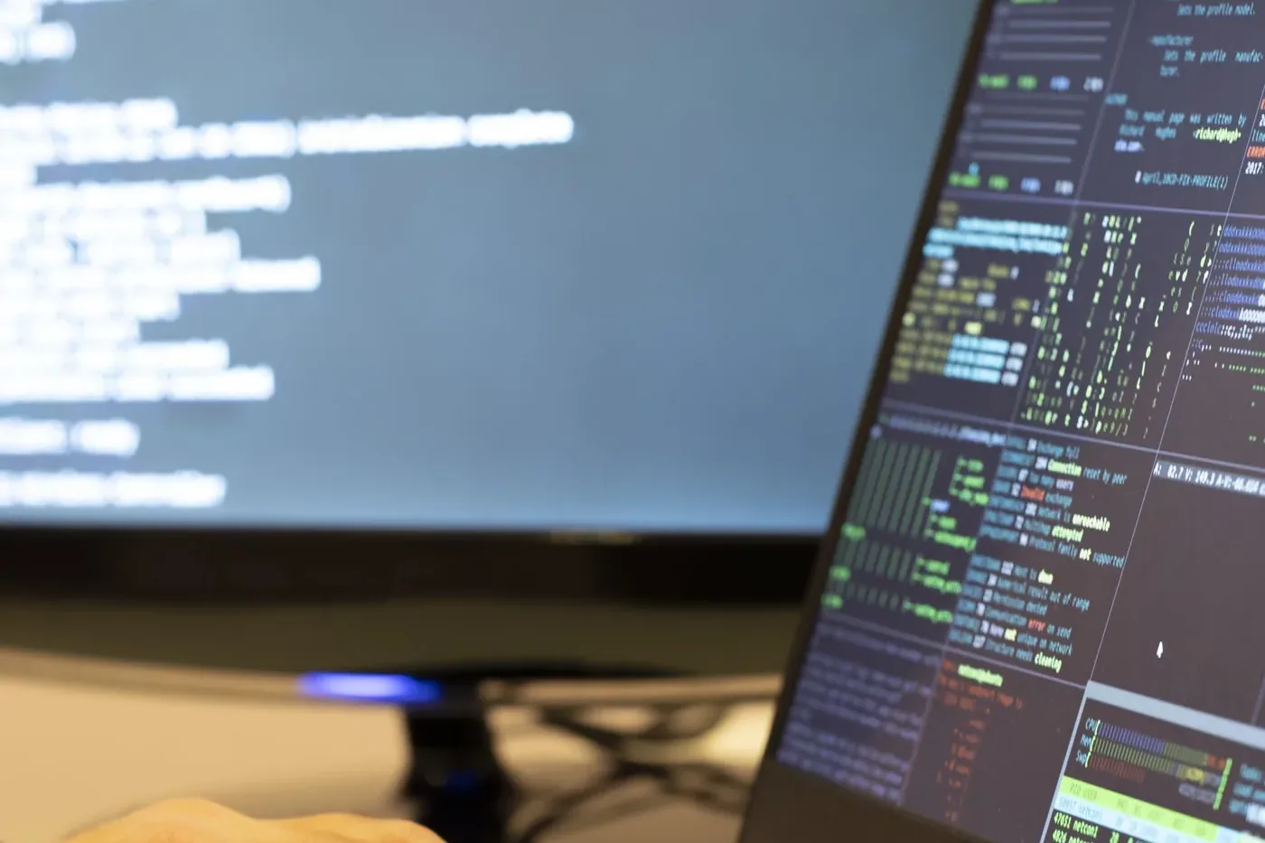 Close-up of two monitors showing log lines and coloured terminal output