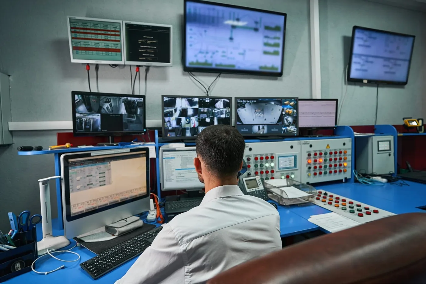 Control room with an operator at a console full of screens and control panels